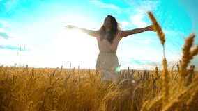 Beauty girl outdoors enjoying nature wheat field slow motion video. Beautiful girl in white dress running nature freedom happiness hands to the side on field at sunset light and the blue lifestyle sky