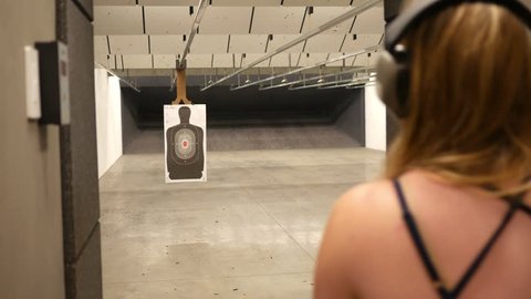 Woman shoots at a target of a man on an indoor gun shooting firing range