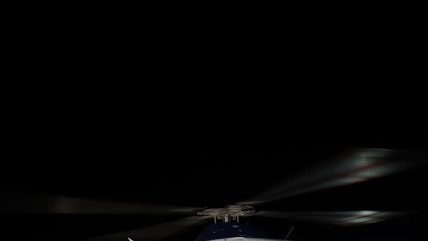 Close up of helicopter blades spinning against a dark sky
