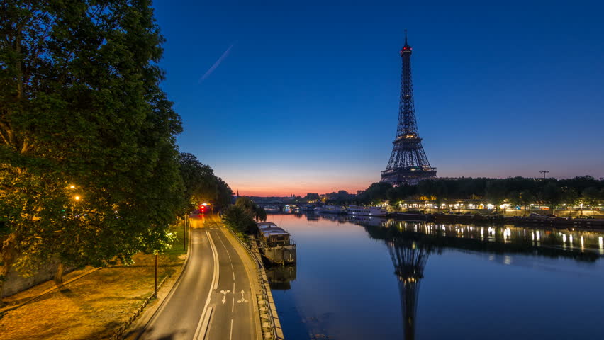Eiffel Tower and the Seine river night to day transition timelapse before sunrise, Paris, France. Morning view from Bir-Hakeim bridge with reflections on water