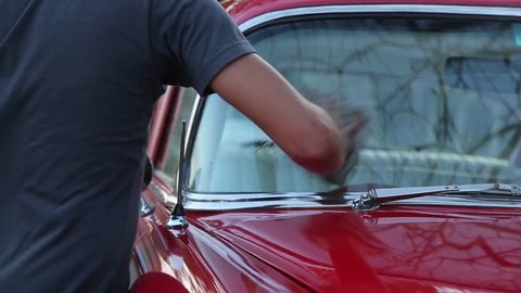 Detail Shot of a man washing a bright red vintage car 