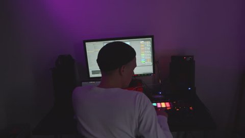 Music producer making music in dark room.
