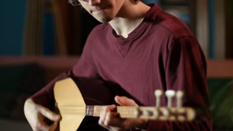 Closeup on the fingering on a beautifully lit saz being performed by a young man.