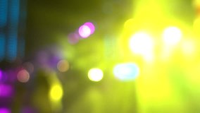 Entertainment concept. Defocused people are dancing at a party. Bright bokeh disco lights and silhouettes of dancing people as background for video editing or a beautiful backdrop.