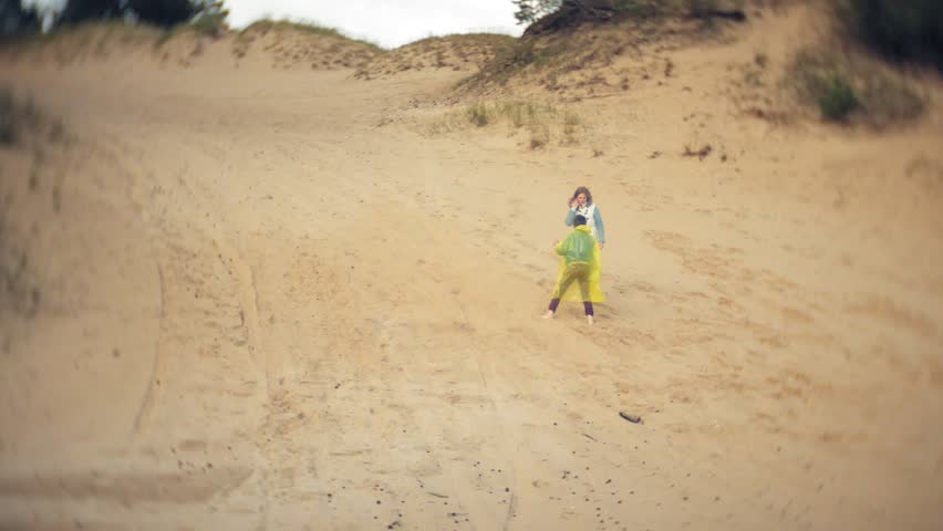 The mother plays with her son in a raincoat and runs down the sea at the beach 4k