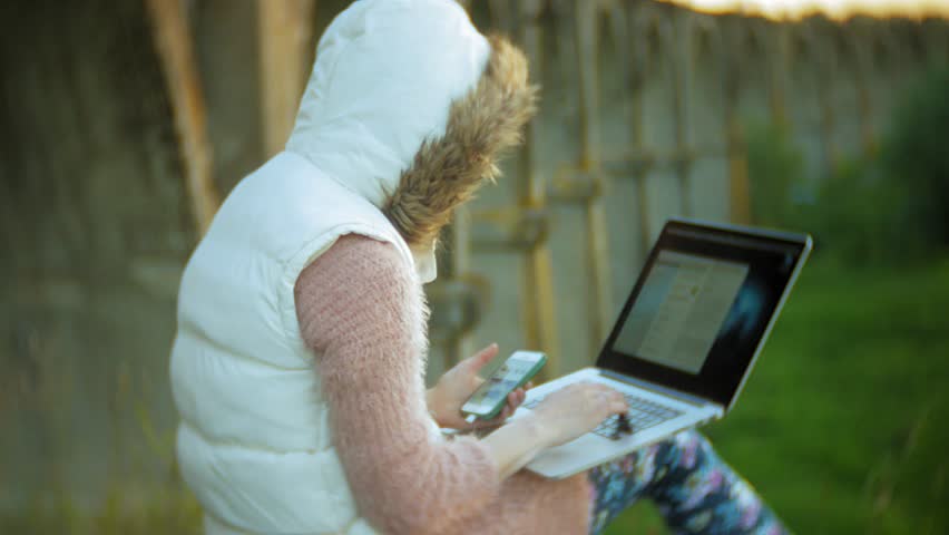 Young woman working on laptop near old vintage railway bridge. 4k