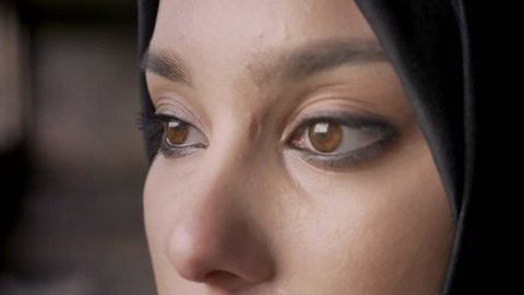 Close portrait of young muslim woman's eyes looking at camera in hijab, sad and depressed expression