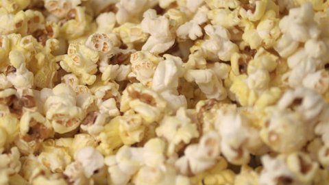 Fresh hot popcorn mixing in popcorn machine. Popcorn background. Close up of popcorn production in slow motion. Cinema pop corn background