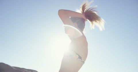 Beautiful girl wearing bikini on the beach doing her hair on summer vacation RED DRAGON