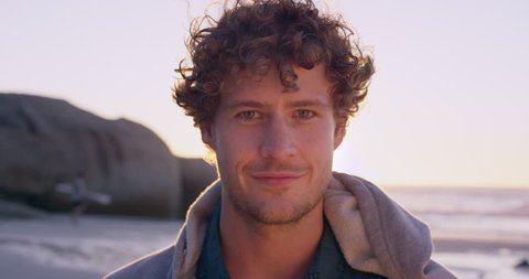Portrait of attractive man smiling on beach at sunset in slow motion RED DRAGON