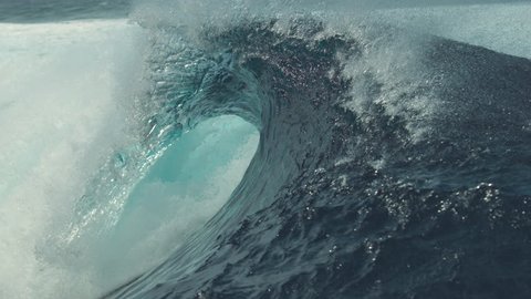 SLOW MOTION, CLOSE UP: Big splashing barrel wave rushes towards the coast of an exotic island in the sunny Pacific. Glassy droplets of water shine in the summer sun as big tube wave crashes wildly.