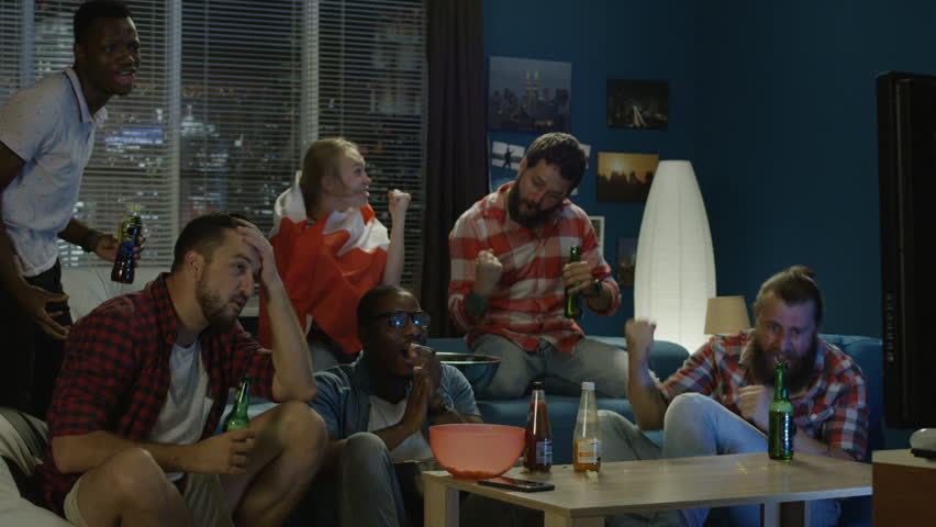 Diverse friends with Canadian flag watching game and celebrating victory of sport steam while chilling at home | Shutterstock HD Video #1013428283