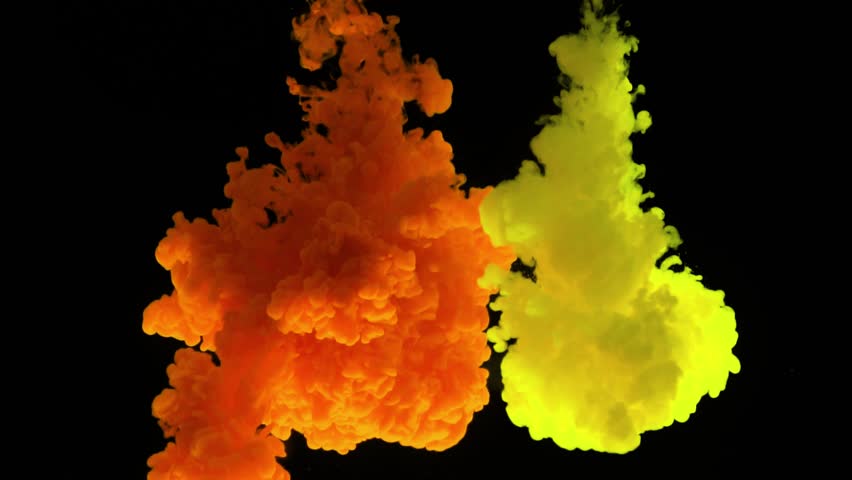 Color paint drops in clear water against a black bcakground in slow motion
