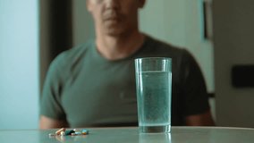man taking pills at home is ill sick slow motion lifestyle video. Healthcare and medical concept disease. male takes a pill and drinks a glass of water indoors