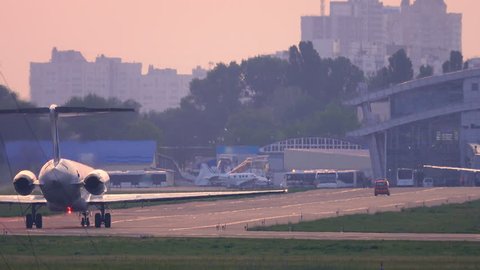 Airplane taxiing on the taxiway to airport terminal after landing at sunset. Back view