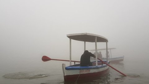 A lake filled with fog in the afternoon. The footage shows boats going into the fog and disappearing from sight. This was taken in a lake in Baguio, Philippines.