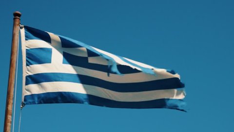 The Greek flag dances in the wind -- in slow motion, in beautiful Santorini, Greece.