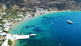 Aerial drone bird's eye view video from famous and picturesque bay and fishing village of Vathi with iconic whitewashed church of Taxiarhis and turquoise clear waters, Sifnos island, Cyclades, Greece