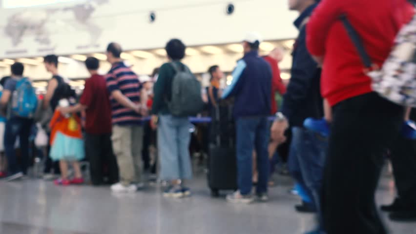 
Blurred defocused clip of passengers check in at the check-in counter at the international airport. Royalty high-quality stock clip of people waiting in line. The subject and background out of focus