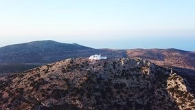 Aerial drone bird’s eye view video of iconic Monastery of Agios Symeon built on a cliff with stunning view to picturesque port of Kamares and Aegean sea, island of Sifnos, Cyclades, Greece