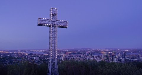 AERIAL: Flying over the cross structure in a forest at night on Mont Royal, It overlooks the city of Montreal, Canada