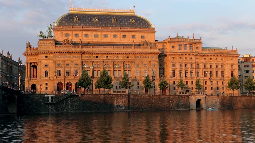 View of the National Theater in Prague over the river, after which the boats are passing.