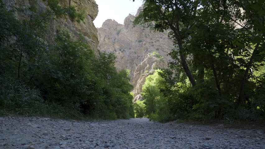 A hiker walking up a gravel mountain trail on a bright warm summer afternoon up Rocky Canyon in Provo, UT.