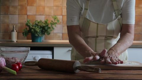 Old woman is making dough for dumplings, slow motion video