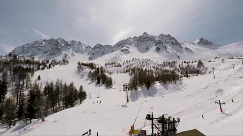 Slow aerial view of a French Ski resort with tilting and panning motion and beautiful mountains in the background