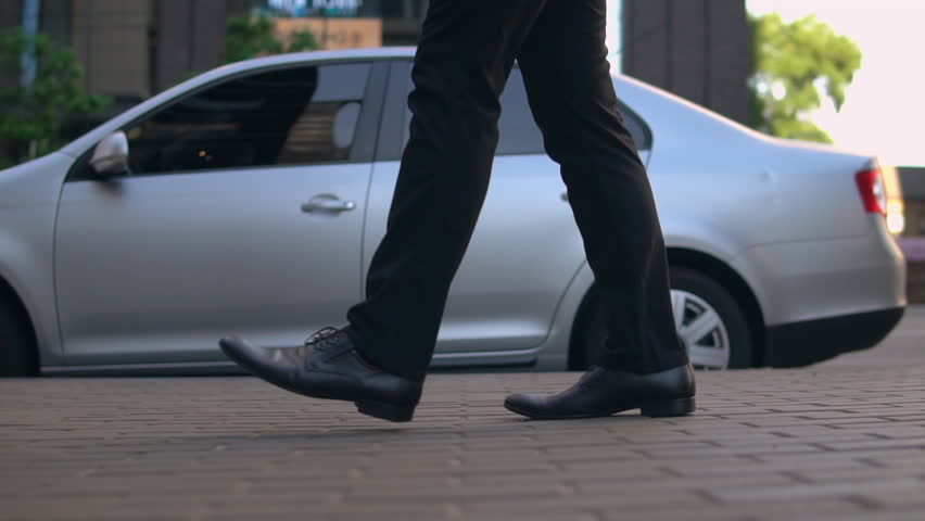 A man is walking along beautiful street. His shoes are formal and shiny. Royalty-Free Stock Footage #1013460752