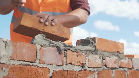 Close-up shut of Bricklayer working on a blue sky background