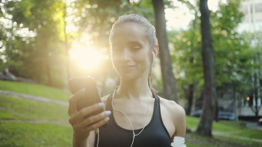 Portrait young woman use smartphone drink water in park sun outdoor health hand girl tree sport fitness summer nature internet technology runner exercise phone workout mobile cellphone