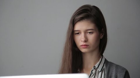 young businesswoman working via computer, grey background.