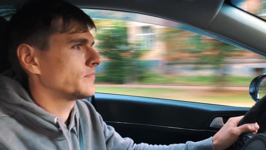 Handsome man driving a car, cityscape outside | Shutterstock HD Video #1013470277