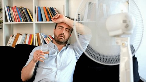 The video is about one stressed man sweating because summer heat and drinking a glass of water.The shot is fixed on the man.
