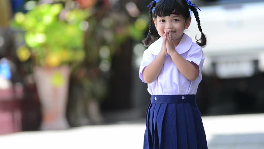cute Asian school girl in action of Thai greeting style. Thai greeting meaning is to say hello,welcome to other people and also thankful to other. In Thai language, it is called Sawatdee.