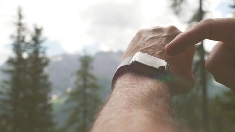 Slow motion close up of hiker man using a smart watch in a mountain trail at sunset or sunset for healthy exercises. Sport and technology. Arkistovideo