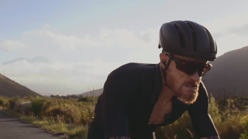 Close up of strong and muscular sportsman riding bicycle outdoors. Fit male cyclist cycling hard outdoors, focus on muscular legs pedaling bicycle.
 Royalty-Free Stock Footage #1013479541