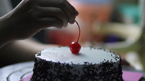 Bakery chef put cherry fruit decorate on cake cream. Concept Bakery chef, Making cake, bakery business
