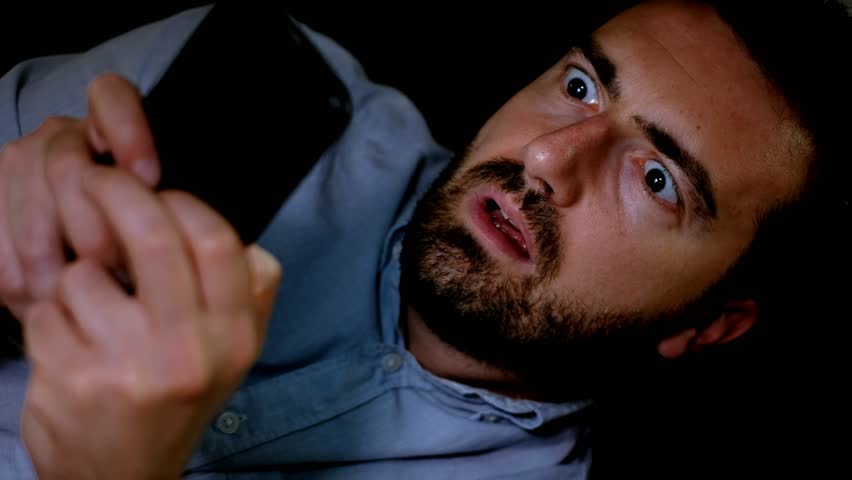 The video is about one surprised man reading unexpected news on the mobile phone at night.The shot is fixed on the man Royalty-Free Stock Footage #1013486369