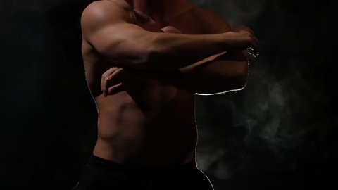 Man is dancing a strip . Black background. Slow motion