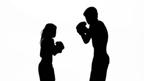 Men with a girl kickboxing gloves beating in the ring . Silhouette. White background. Slow motion - Powered by Shutterstock - Get 15% off with code: PIKWIZARD15
