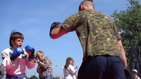 Kherson, Ukraine - 26th of May 2018: 4K Katran fighting club performs at the KhersOn Festival - Boxing session of a child with Master of Jiu-jitsu outdoors
