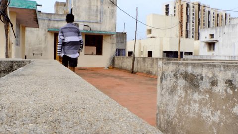 The young man walking over the top of the floor, back view shot of young boy walking on terrace