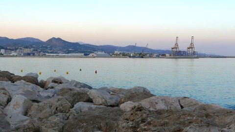 A shot of the Malaga bay in the south of Spain at sunset. The harbor is in the background and the sea is calmed.