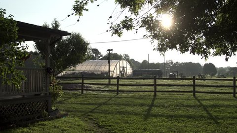 Greenhouse on a local small farm at sunrise with the sun rising behind it.