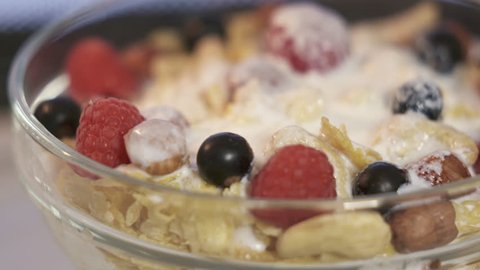 Corn flakes with nuts and fresh berries rotating inside microwave. Warming up cornflakes with milk or yogurt.