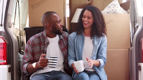 Couple Taking A Break In Back Of Removal Truck On Moving Day