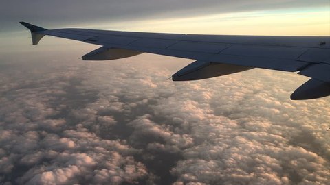 Cloudse past a plane wing during sunset.