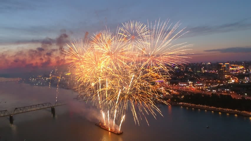 Exploding fireworks over the river. Golden big shiny fireworks in the glowing show. New Year